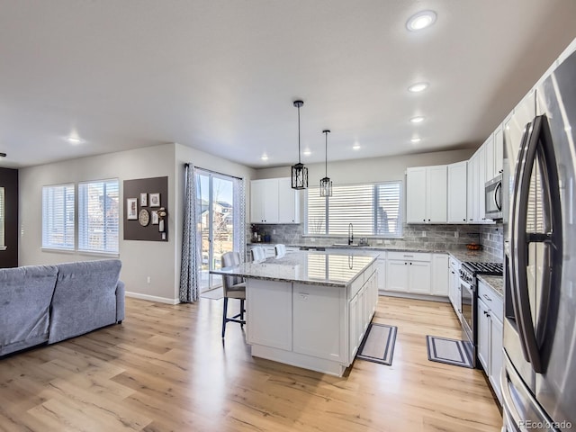 kitchen featuring stainless steel appliances, a kitchen island, and plenty of natural light