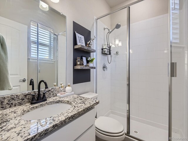 bathroom with vanity, toilet, and a shower with door