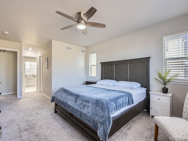 bedroom featuring ceiling fan, light colored carpet, and ensuite bathroom