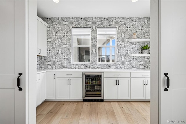 bar with light wood-style floors, wallpapered walls, and beverage cooler