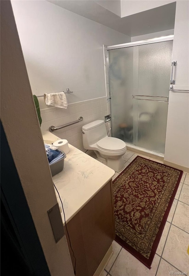 bathroom featuring tile walls, a shower with shower door, vanity, toilet, and tile patterned floors