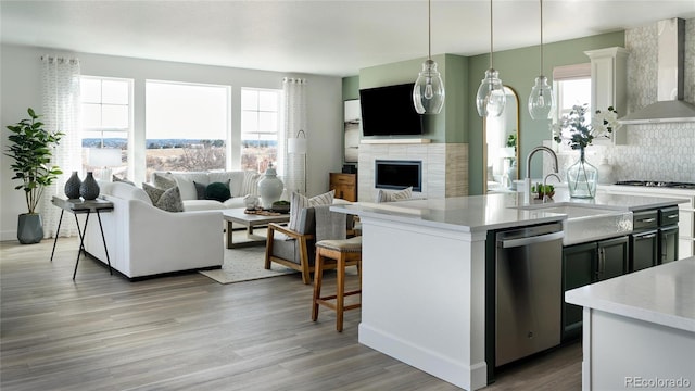 kitchen featuring decorative light fixtures, stainless steel appliances, a healthy amount of sunlight, and wall chimney range hood