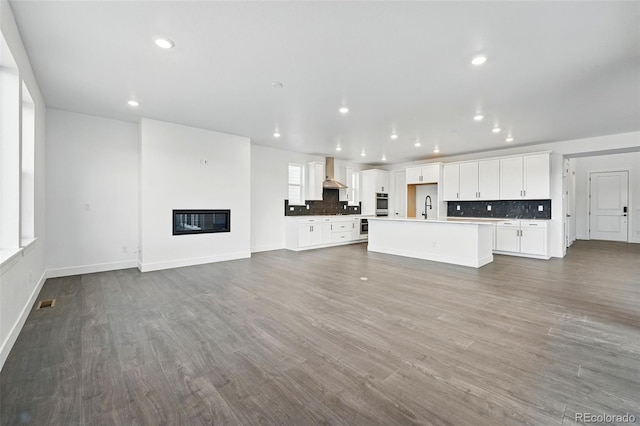 16549 Black Rose Cir, Parker, CO 80134 - unfurnished living room with baseboards, wood finished floors, recessed lighting, a sink, and a glass covered fireplace