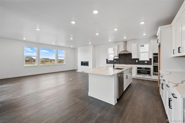 16549 Black Rose Cir, Parker, CO 80134 - kitchen with stainless steel appliances, decorative backsplash, dark wood-style floors, a kitchen island with sink, and wall chimney exhaust hood