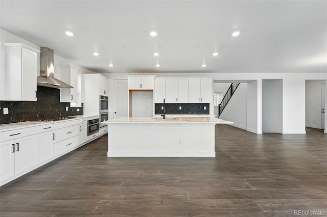 16549 Black Rose Cir, Parker, CO 80134 - kitchen with a kitchen island with sink, gas cooktop, wall chimney exhaust hood, dark wood finished floors, and a sink