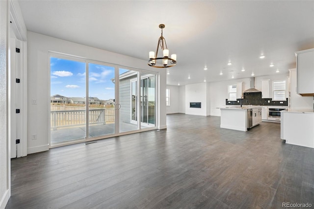 16549 Black Rose Cir, Parker, CO 80134 - kitchen with dark wood finished floors, open floor plan, wall chimney range hood, a center island, and a notable chandelier