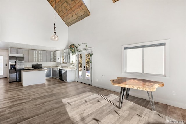 kitchen featuring hardwood / wood-style floors, pendant lighting, high vaulted ceiling, and black appliances