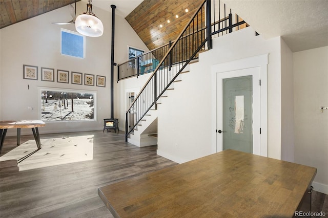 interior space featuring dark hardwood / wood-style flooring, a wood stove, high vaulted ceiling, and wooden ceiling