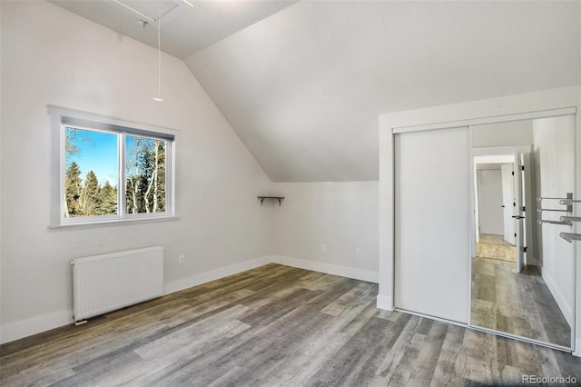 bonus room with radiator, hardwood / wood-style floors, and vaulted ceiling