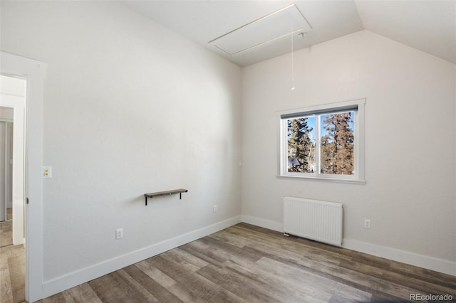 empty room with wood-type flooring, radiator, and vaulted ceiling