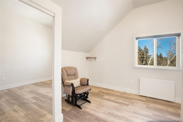 sitting room with light hardwood / wood-style floors, lofted ceiling, and radiator