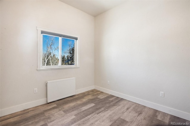 unfurnished room with hardwood / wood-style flooring and radiator