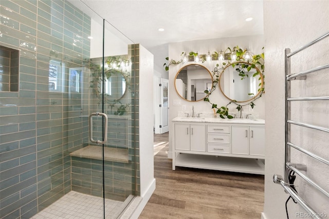 bathroom with a shower with shower door, wood-type flooring, and vanity