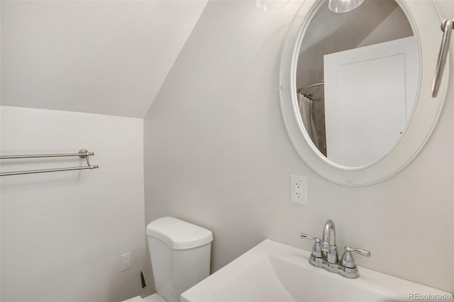 bathroom featuring toilet, sink, and vaulted ceiling