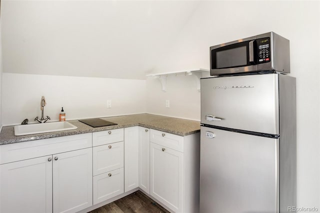 kitchen with stainless steel appliances, white cabinetry, lofted ceiling, and sink