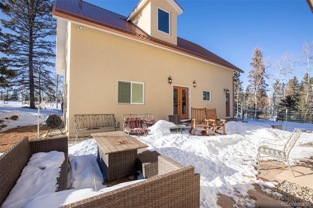 snow covered house with outdoor lounge area and french doors