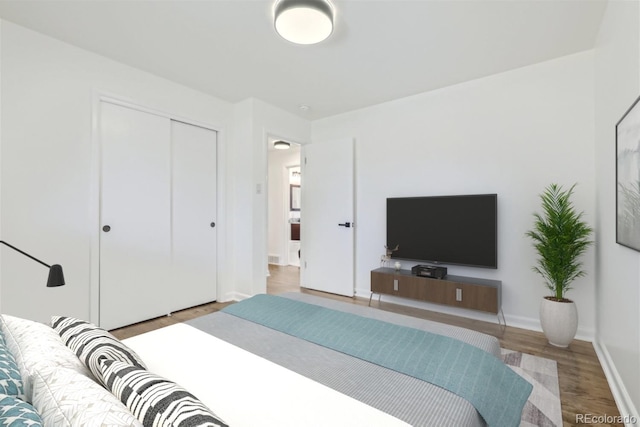 bedroom with a closet, wood finished floors, and baseboards