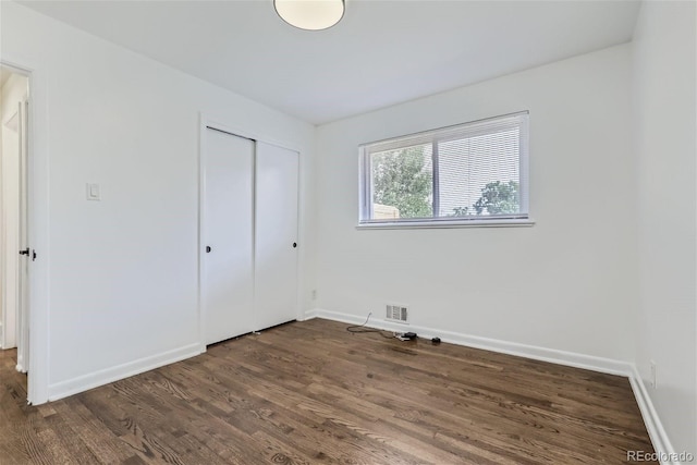 unfurnished bedroom featuring dark hardwood / wood-style flooring and a closet