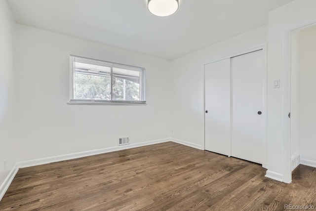 unfurnished bedroom featuring dark wood-type flooring and a closet