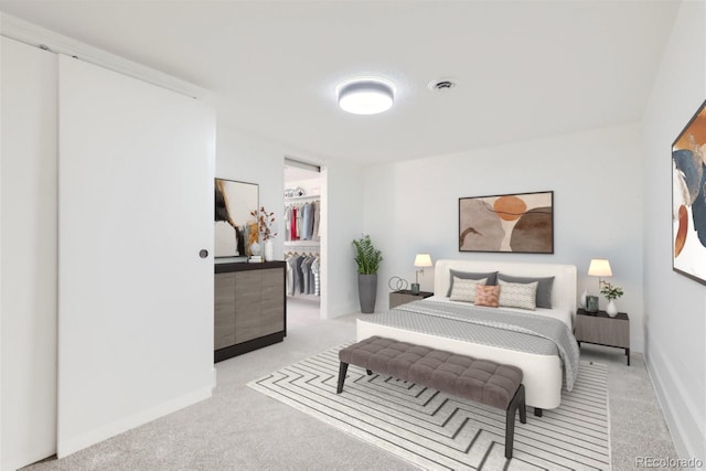 carpeted bedroom featuring a walk in closet and a closet