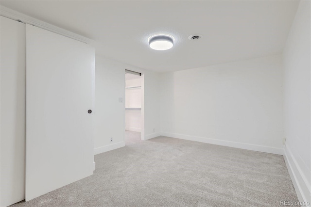 spare room with light carpet, visible vents, and baseboards