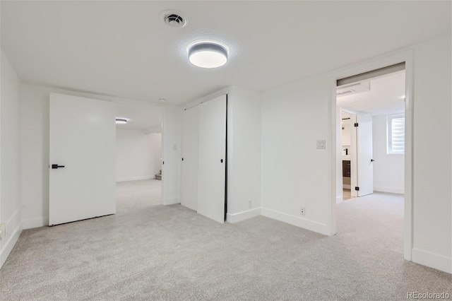 empty room with baseboards, visible vents, and light colored carpet