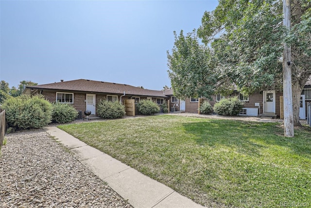 ranch-style home featuring brick siding, a front yard, and fence