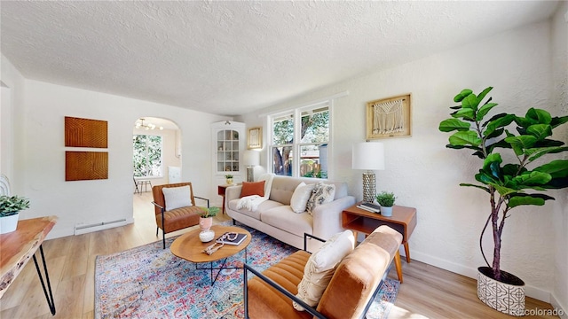 living room featuring arched walkways, a baseboard heating unit, a textured ceiling, and wood finished floors