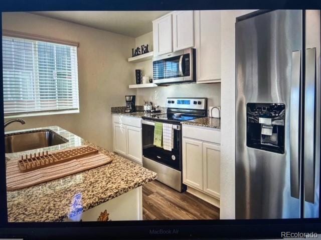 kitchen featuring white cabinetry, sink, light stone counters, and appliances with stainless steel finishes