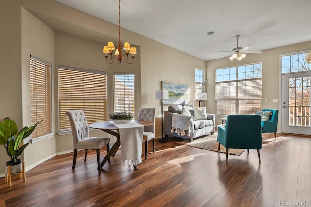 dining space with ceiling fan with notable chandelier and dark hardwood / wood-style flooring