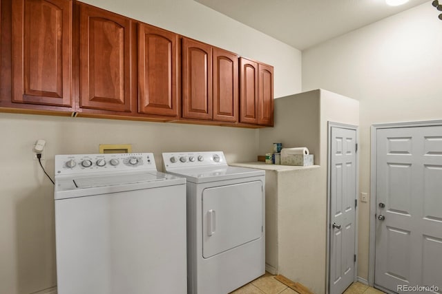 laundry area featuring washer and clothes dryer, cabinets, and light tile patterned flooring