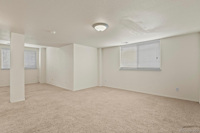 spare room with light colored carpet and a textured ceiling