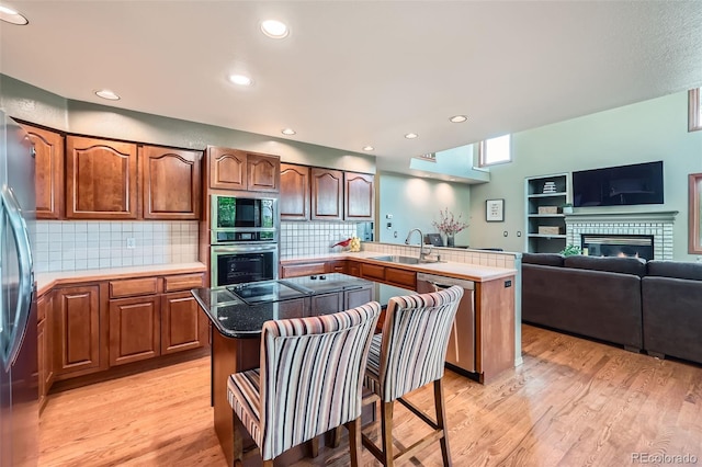 360 Morning Star Ln, Lafayette, CO 80026 - kitchen featuring black appliances, a peninsula, light wood finished floors, a brick fireplace, and open floor plan