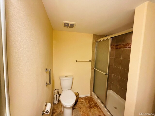 bathroom with tile patterned floors, walk in shower, and toilet