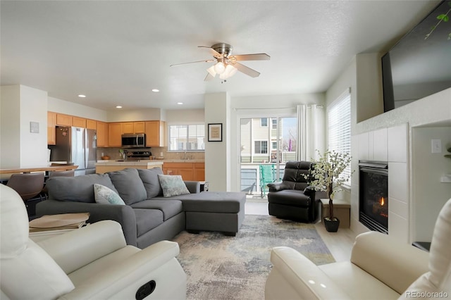 living room featuring light wood-style floors, ceiling fan, recessed lighting, and a tile fireplace