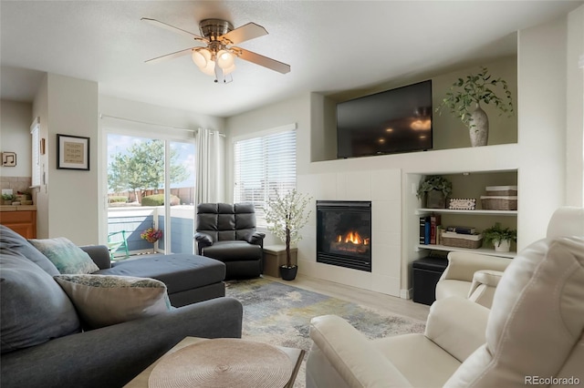 living area featuring ceiling fan, a fireplace, and wood finished floors