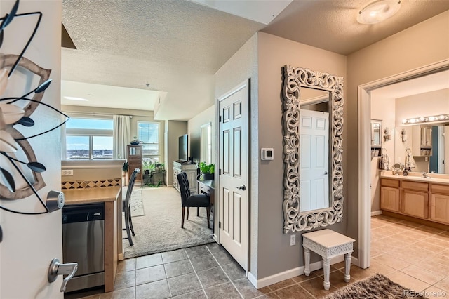 interior space featuring a textured ceiling, light tile patterned floors, and baseboards