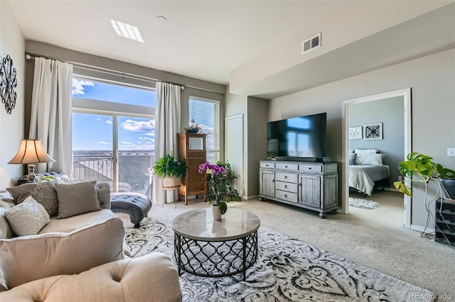 living area featuring light colored carpet, visible vents, and baseboards