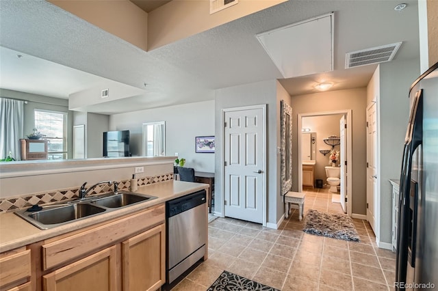 kitchen featuring dishwasher, light countertops, a sink, and visible vents