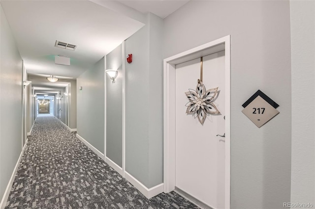 corridor with carpet floors, visible vents, and baseboards