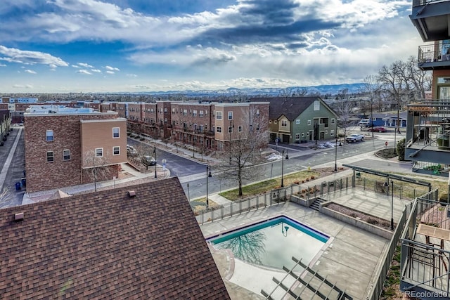 community pool with a patio area, fence, and a mountain view