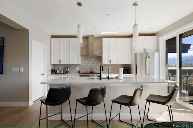 387 Bear Trl, Winter Park, CO 80482 - kitchen with high quality fridge, wall chimney exhaust hood, a sink, wood finished floors, and decorative backsplash