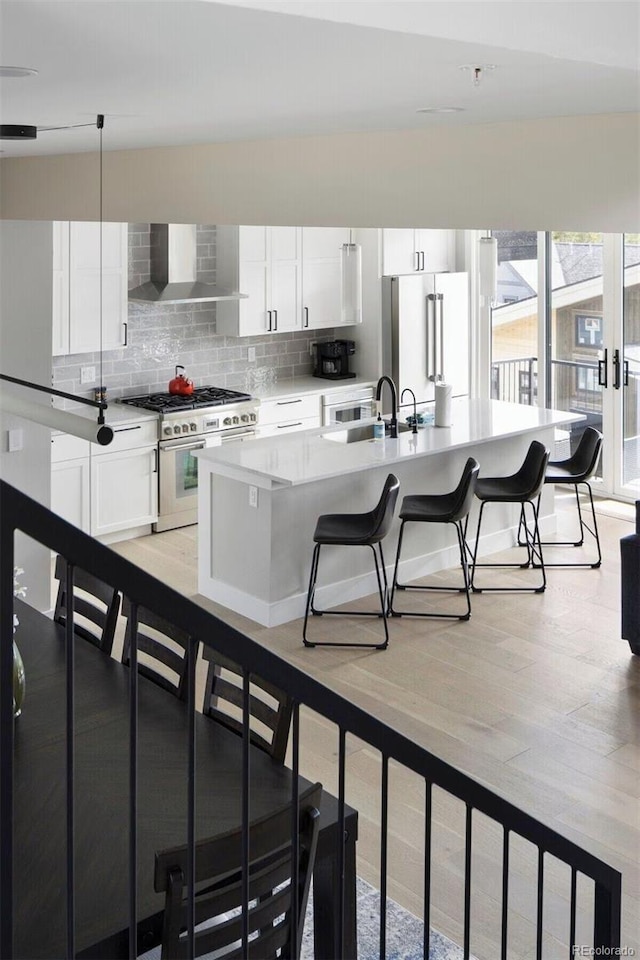 387 Bear Trl, Winter Park, CO 80482 - kitchen with wall chimney range hood, high quality appliances, a sink, white cabinetry, and backsplash