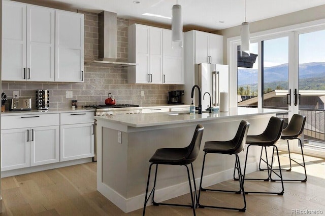 387 Bear Trl, Winter Park, CO 80482 - kitchen with wall chimney range hood, appliances with stainless steel finishes, a sink, decorative backsplash, and light wood-type flooring