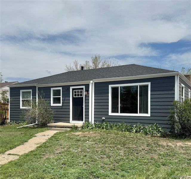 view of front of property featuring a front lawn and a shingled roof