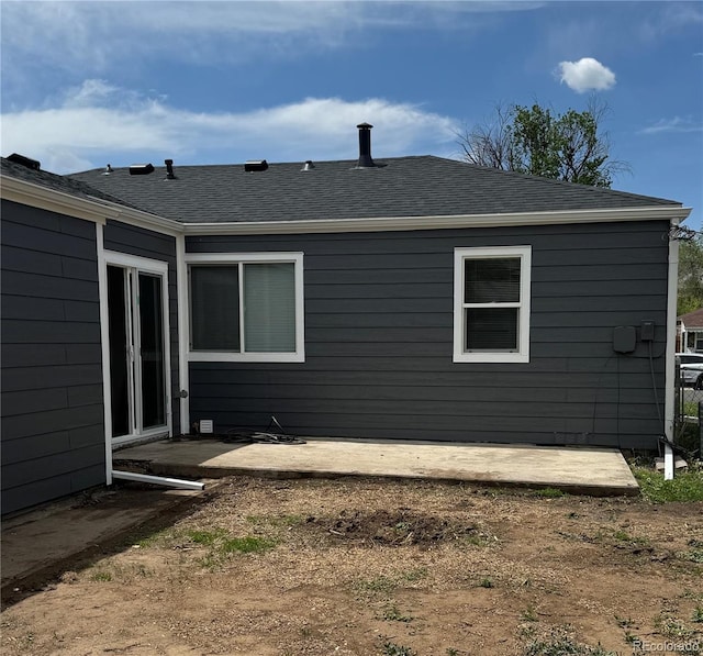 rear view of property with a patio area and roof with shingles