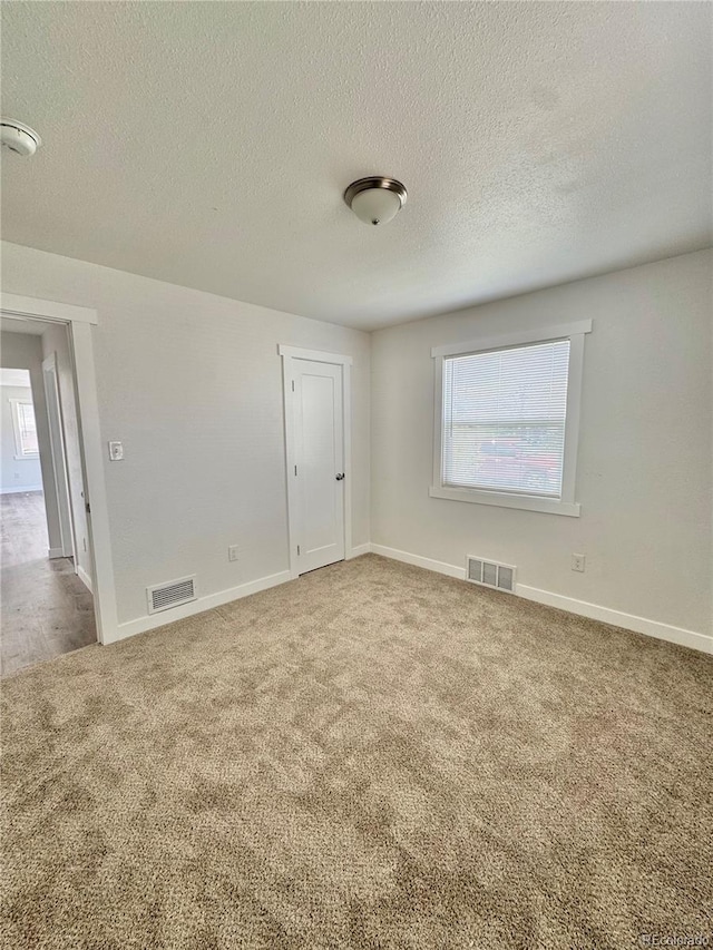 unfurnished room featuring carpet floors, healthy amount of natural light, a smoke detector, a textured ceiling, and baseboards