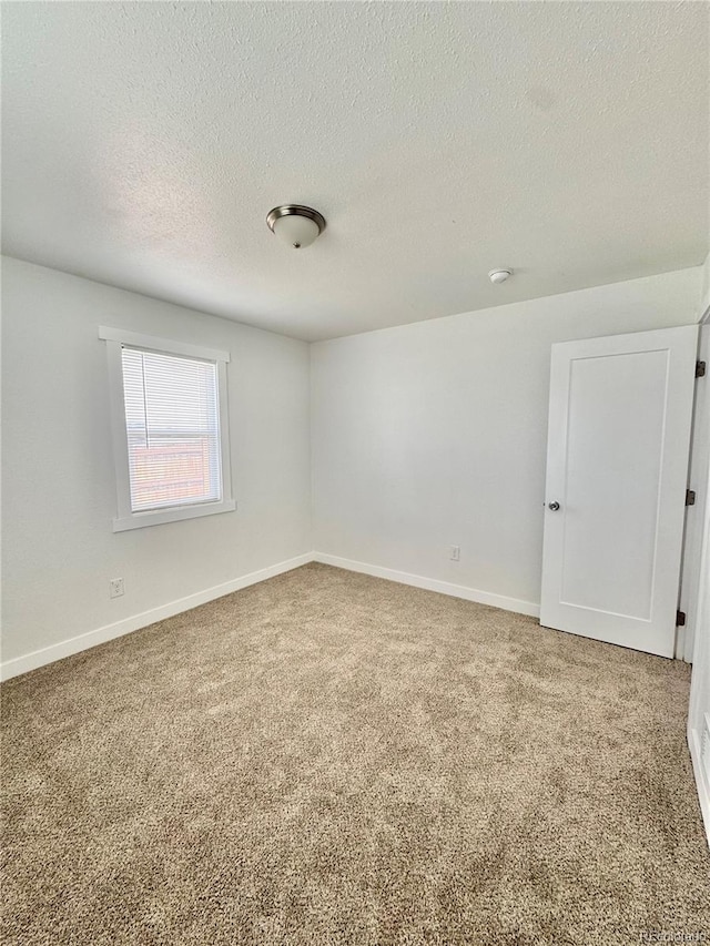 empty room featuring carpet, a textured ceiling, and baseboards