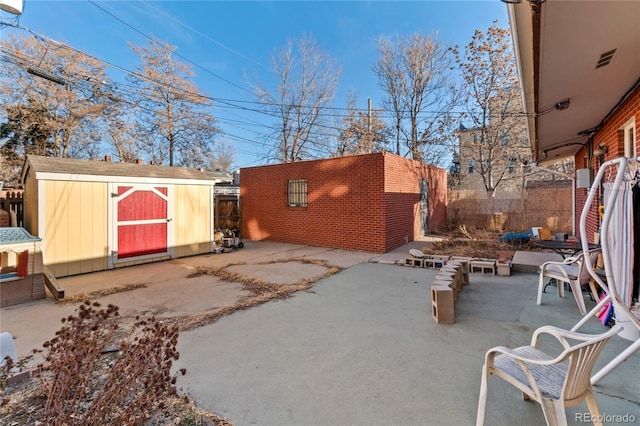 view of patio with an outbuilding, a storage shed, and fence