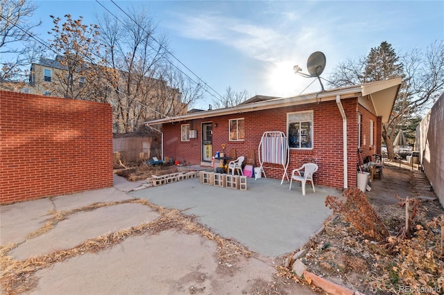 rear view of property featuring entry steps, a patio, fence, and brick siding